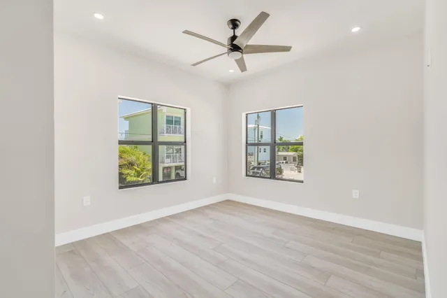 an empty room with wooden floor fan and windows