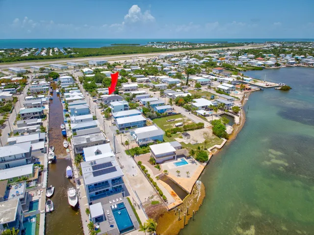 an aerial view of residential houses with outdoor space and ocean view
