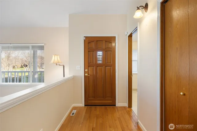 a view of a hallway with wooden floor and a bathroom
