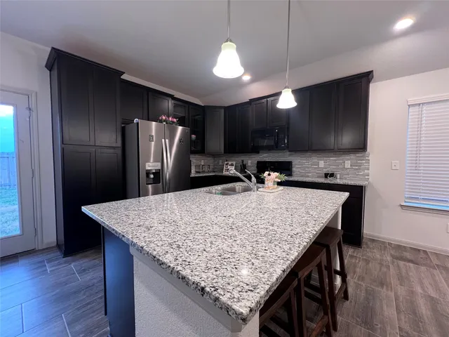 a kitchen with stainless steel appliances granite countertop refrigerator sink dining table and chairs