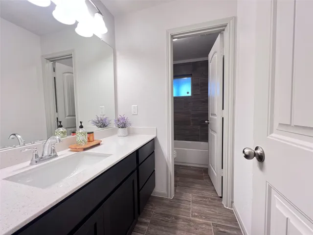 a bathroom with a granite countertop sink a mirror and a bathtub