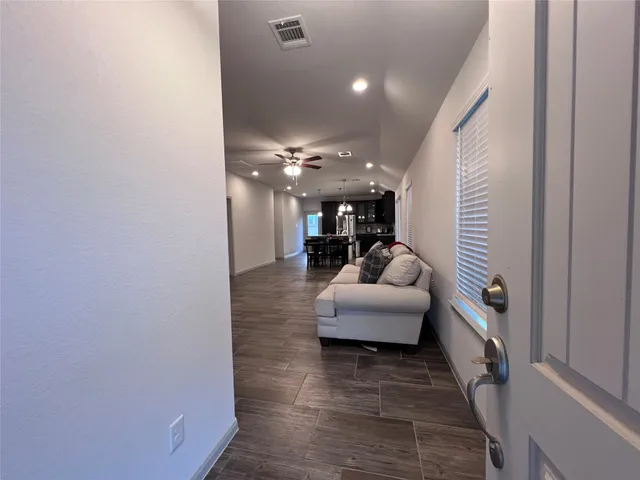 a hallway with couches and a potted plant with wooden floor