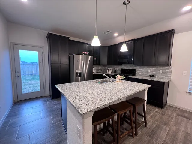 a kitchen with stainless steel appliances granite countertop wooden floors a refrigerator and a sink