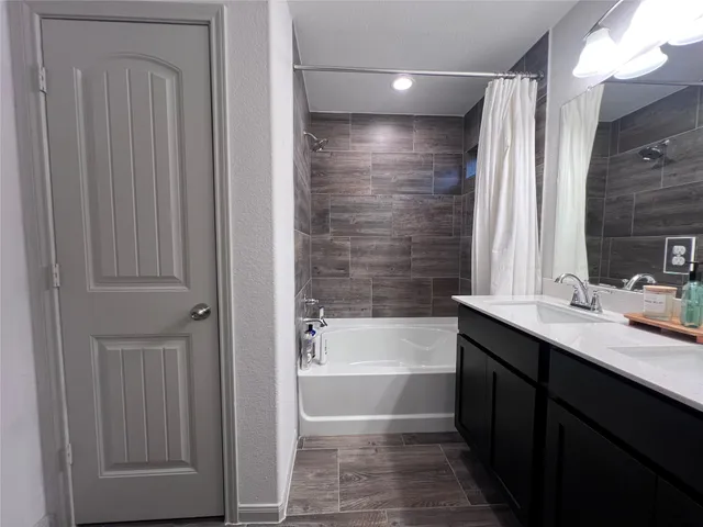 a bathroom with a tub sink vanity and a mirror