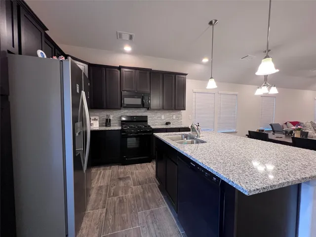 a kitchen with kitchen island a counter top a stove a refrigerator and a sink