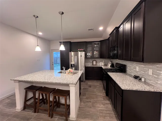 a kitchen with granite countertop cabinets a sink a counter space and stainless steel appliances