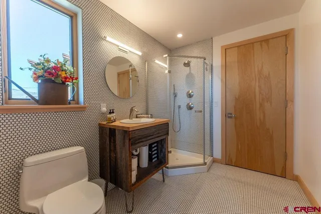 a bathroom with a toilet sink vanity granite and mirror