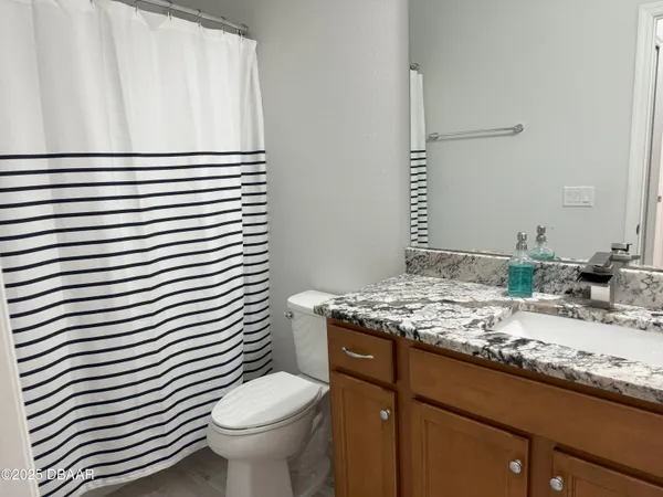 a bathroom with a granite countertop sink toilet and mirror