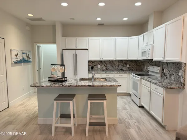 a kitchen with kitchen island granite countertop a sink and white cabinets