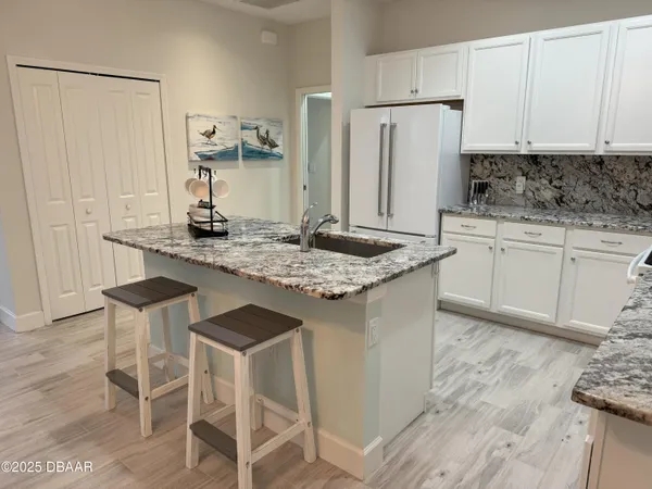 a kitchen with stainless steel appliances granite countertop a table chairs sink and cabinets