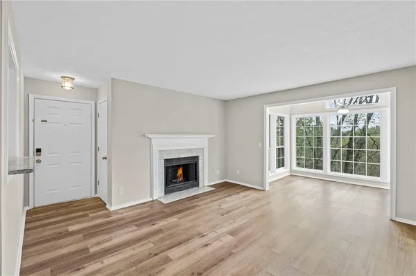 a view of an empty room with wooden floor fireplace and a window