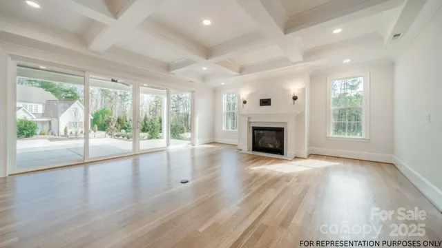 an empty room with wooden floor fireplace and windows