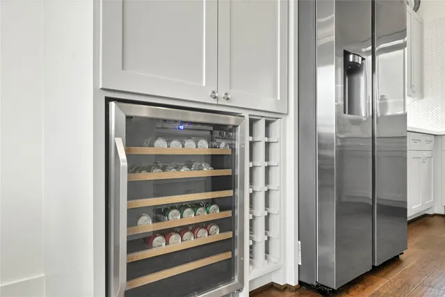 a view of a refrigerator in kitchen and an empty room with wooden floor