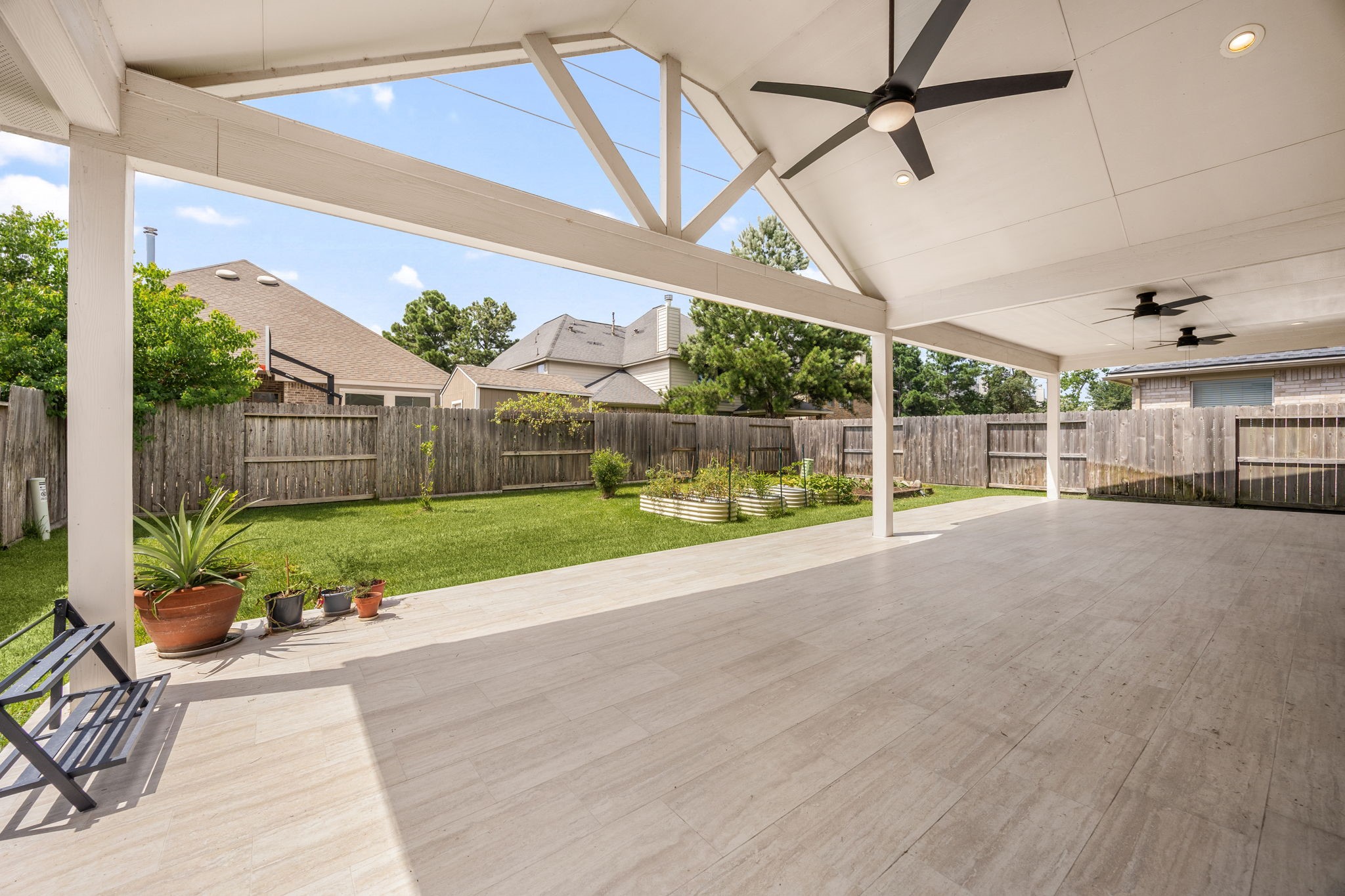 4526 Countrypines Drive Spring, TX 77388 - Photo 32 of 38 Step outside into your private backyard paradise! An enormous covered patio features an elegant vaulted ceiling with exposed truss details, ceiling fans, and premium tile flooring. The massive space overlooks a fully fenced green lawn.