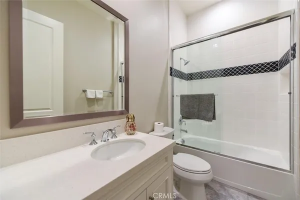 a bathroom with a granite countertop sink toilet mirror and shower