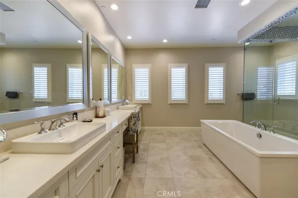 a bathroom with a tub a sink double vanity and a mirror