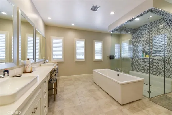 a spacious bathroom with a double vanity sink a large mirror and a bathtub