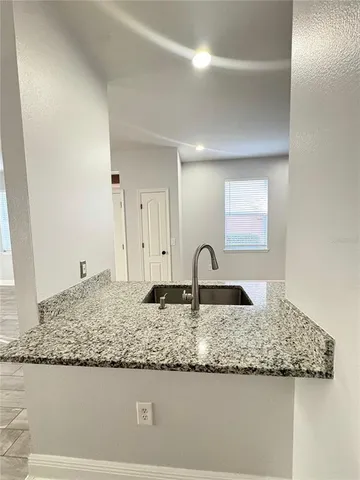 a view of an empty room with kitchen and a window
