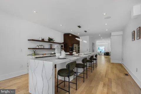 a kitchen with stainless steel appliances kitchen island granite countertop a stove a sink a refrigerator and chairs