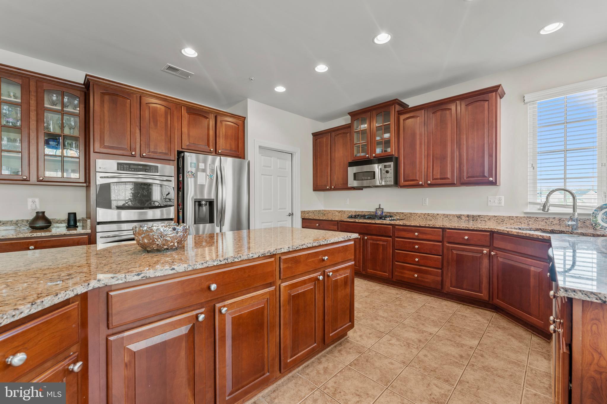 10916 Sir Paul Place Clinton, MD 20735 - Photo 29 of 66 a kitchen with stainless steel appliances granite countertop wooden cabinets a refrigerator and a sink
