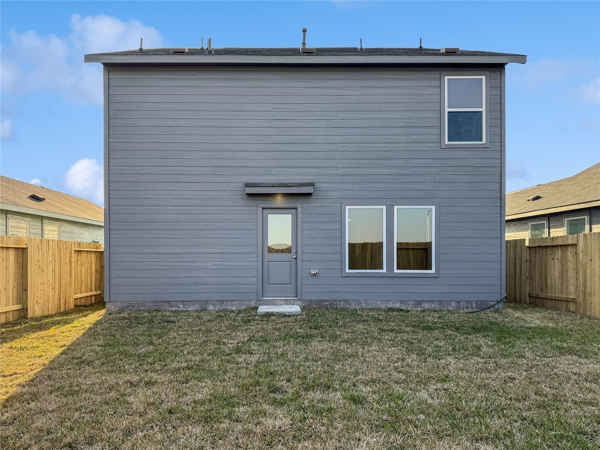 12430 Wild Strawberry Road Houston, TX 77038 - Photo 33 of 34 Private, fully fenced backyard featuring a gray-blue two-story exterior, rear entry door, and multiple windows.