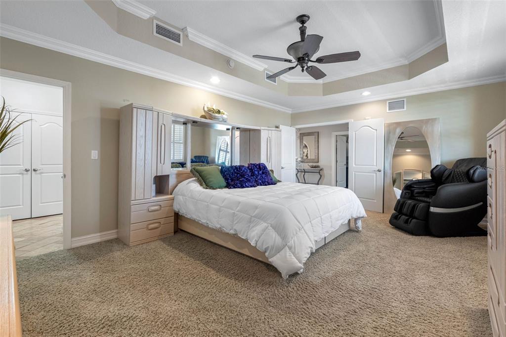 17717 Gulf Boulevard, Unit 702 Redington Shores, FL 33708 - Photo 78 of 99 a spacious bedroom with a bed a couch and a chandelier