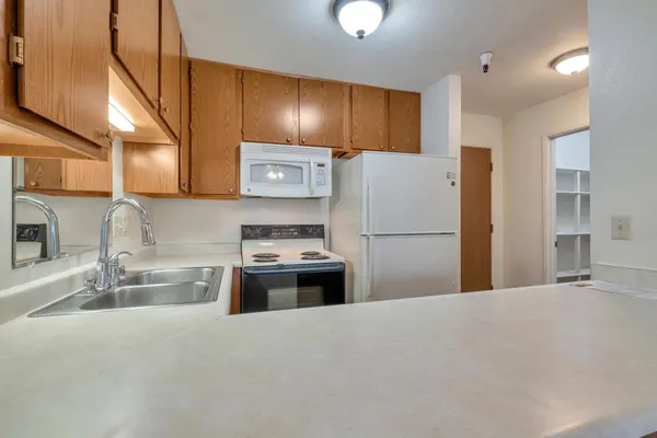a kitchen with stainless steel appliances granite countertop a refrigerator a stove and a sink with wooden floors