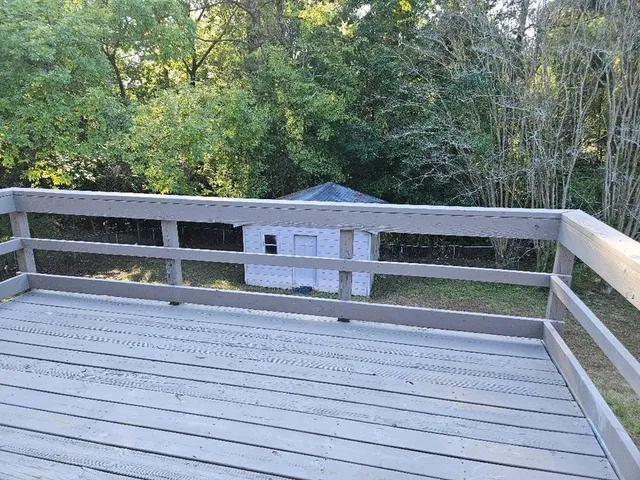 a view of a deck with a large window and wooden fence