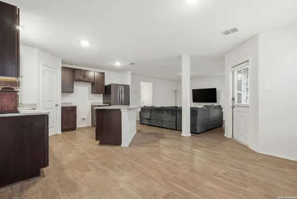 a large kitchen with a stove a refrigerator and a sink with wooden floor