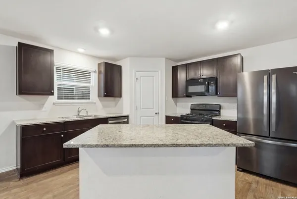 a kitchen with stainless steel appliances granite countertop a sink and a refrigerator