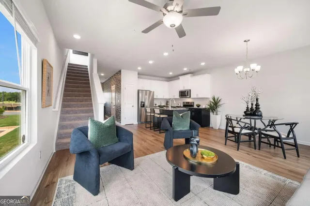 a living room with furniture kitchen view and a large window