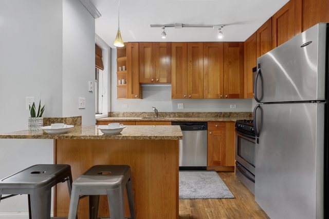 4144 North Sheridan Road, Unit 208 Chicago, IL 60613 - Photo 10 of 24 a kitchen with stainless steel appliances granite countertop a refrigerator a stove a sink and a microwave