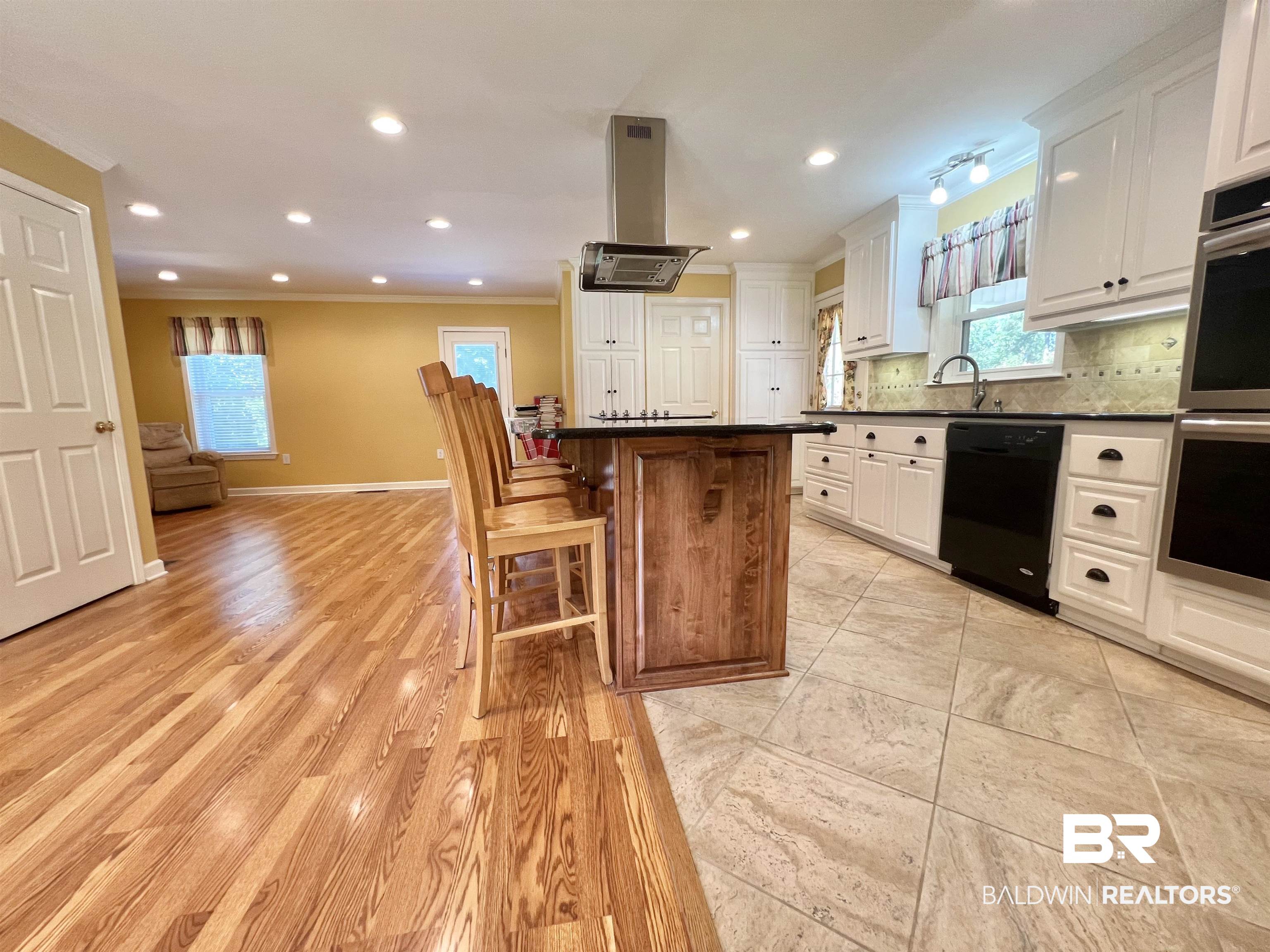 2691 Appleton Road Brewton, AL 36426 - Photo 12 of 60 Kitchen with crown molding, backsplash, a breakfast bar area, island range hood, and black dishwasher