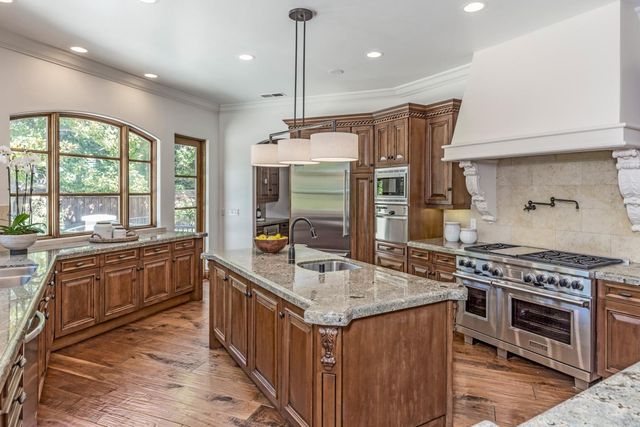 a kitchen with stainless steel appliances granite countertop a stove a sink and a refrigerator