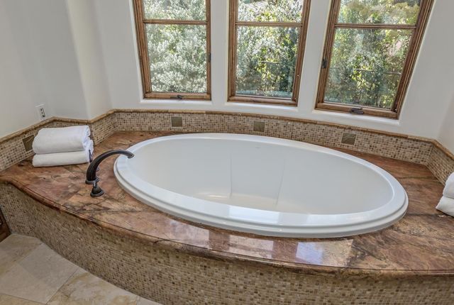 a white bath tub sitting in a bathroom next to a window