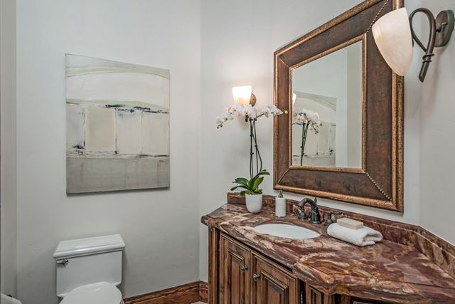 a bathroom with a granite countertop sink vanity mirror and toilet
