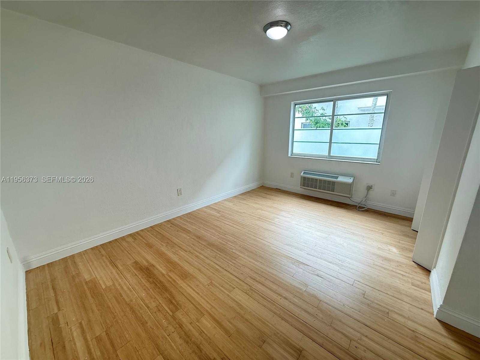 6930 Rue Vendome, Unit 3 Miami Beach, FL 33141 - Photo 14 of 14 an empty room with wooden floor and windows