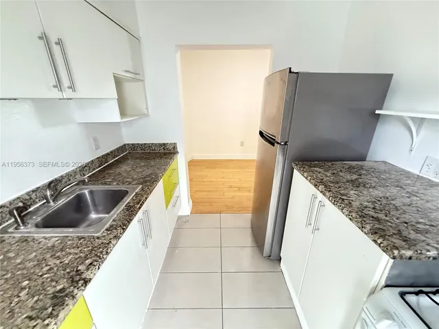 a kitchen with granite countertop a sink a stove and refrigerator