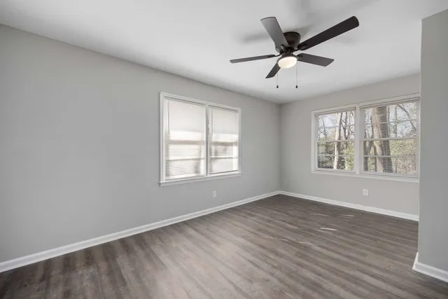 a view of an empty room with wooden floor and a window