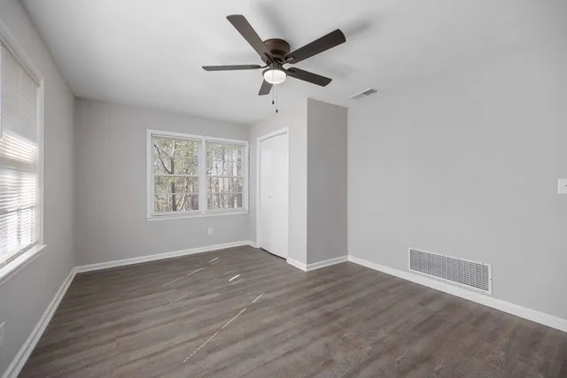 a view of an empty room with wooden floor and a window