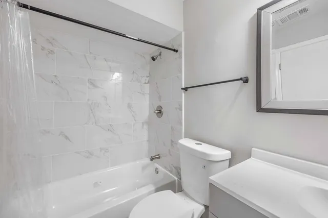 a white toilet sitting next to a bath tub and a shower