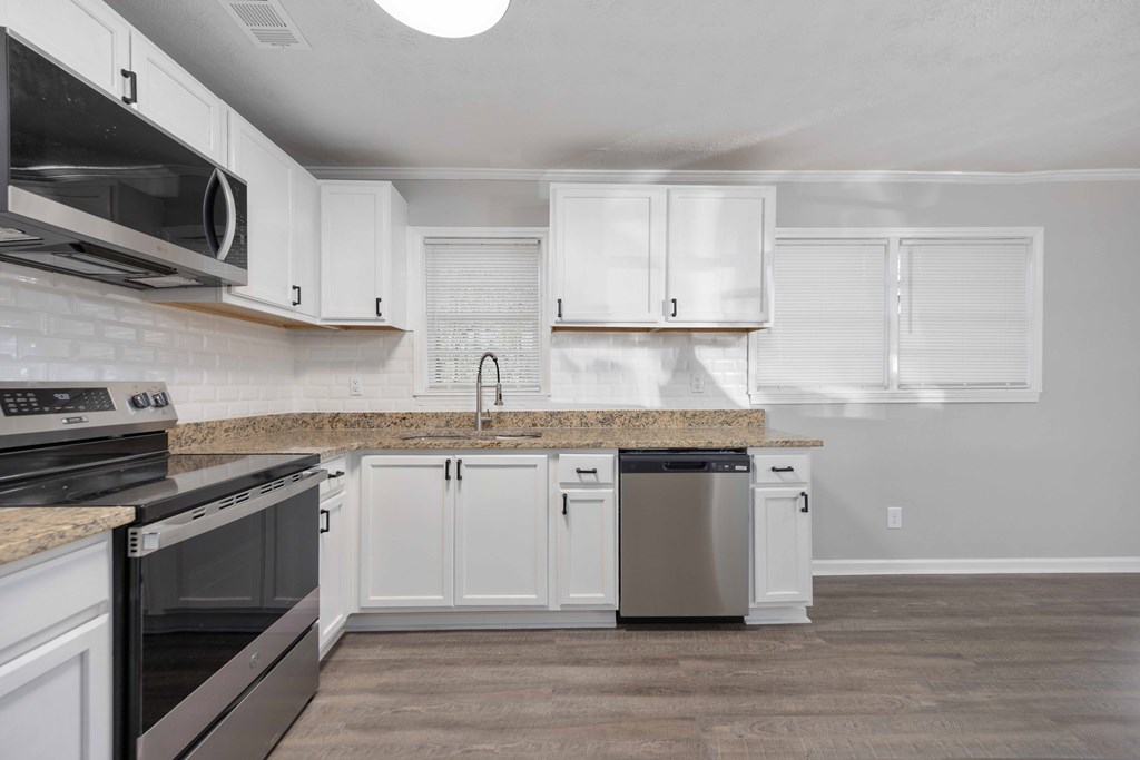 5100 Buckingham Court Columbus, GA 31907 - Photo 6 of 24 a kitchen with stainless steel appliances granite countertop a stove top oven a sink dishwasher and white cabinets with wooden floor