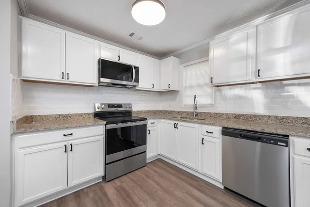 a kitchen with granite countertop cabinets stainless steel appliances and a sink