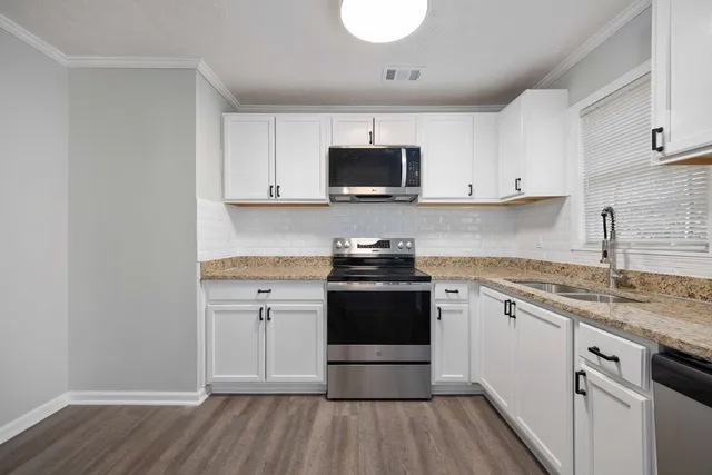 a kitchen with stainless steel appliances granite countertop a stove a sink and a microwave