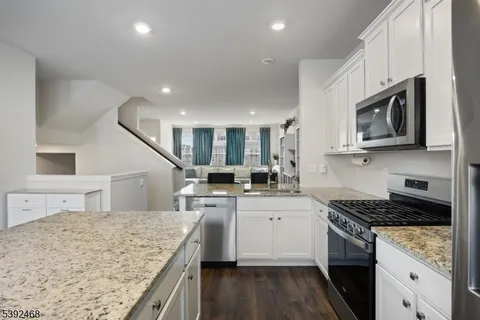 a room with kitchen island a sink dishwasher a dining table and chairs with wooden floor