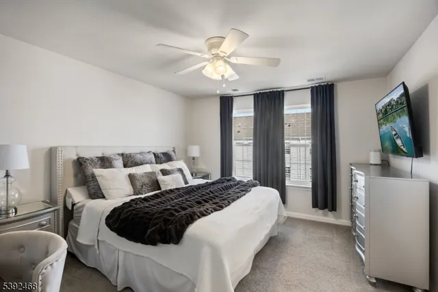 a bedroom with a large bed and a flat tv screen on dresser