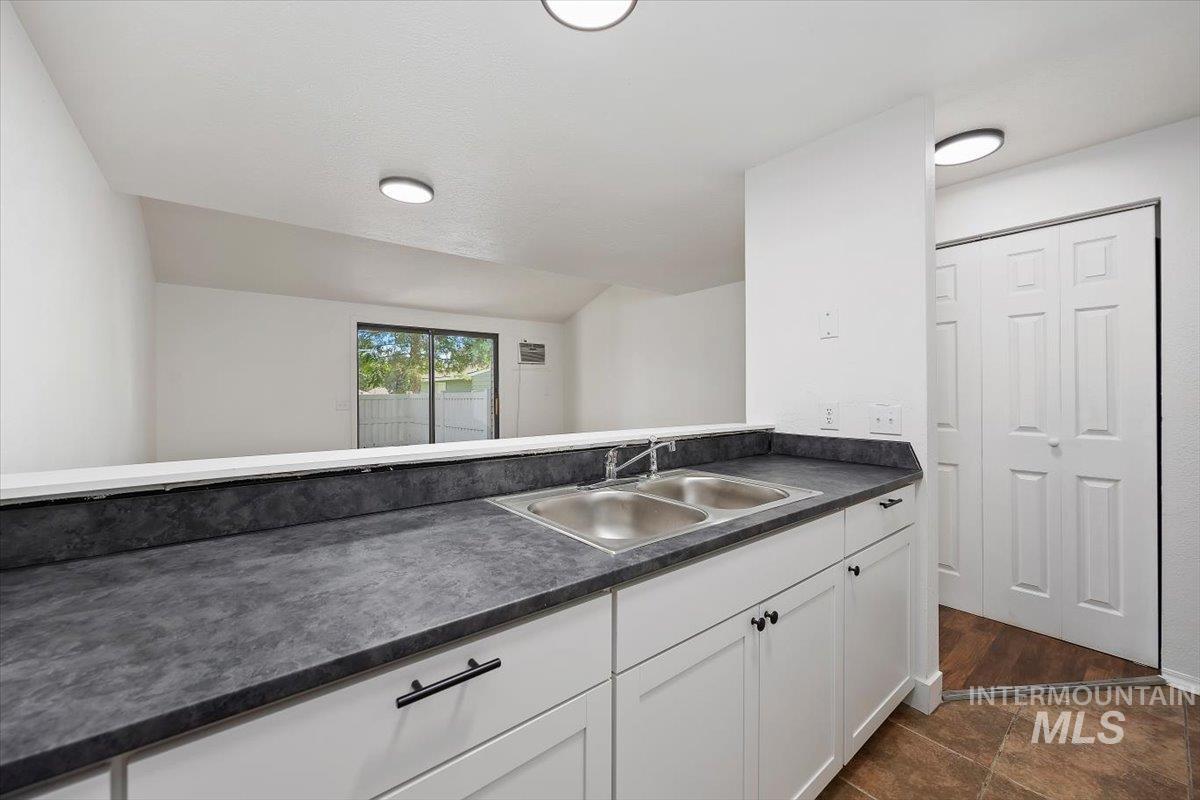259 Pheasant Road, Unit 84 Twin Falls, ID 83301 - Photo 9 of 25 Kitchen counter with dual stainless steel sink, dark textured countertops, and white shaker-style cabinetry