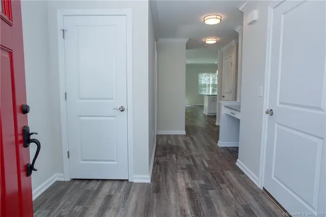 a view of a hallway with wooden floor and a bathroom