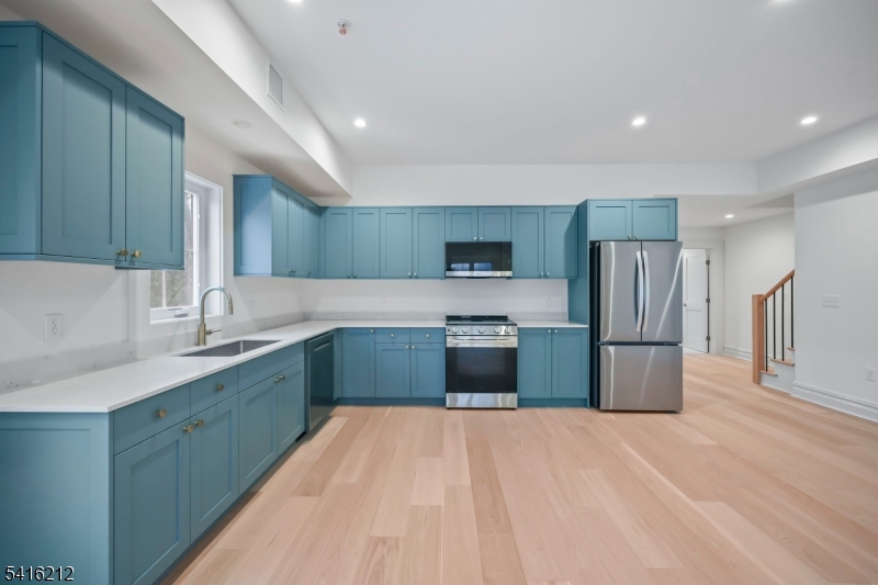 a large kitchen with stainless steel appliances a sink and a refrigerator