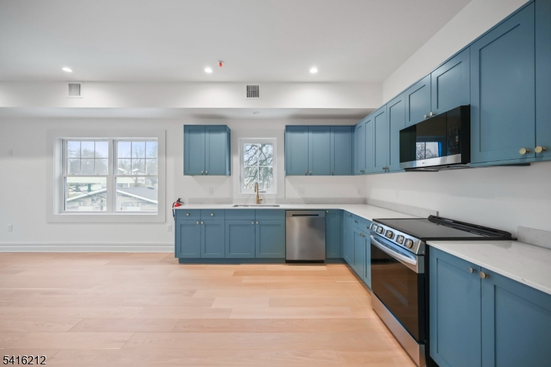 1209 Littleton Road, Unit E Morris Plains, NJ 07950 - Photo 10 of 27 a kitchen with stainless steel appliances granite countertop a stove a sink and a microwave